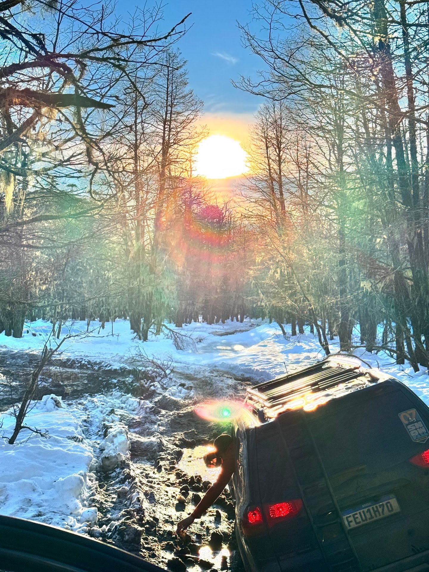 Veículo 4x4 de expedição visto por trás em uma trilha de lama e neve